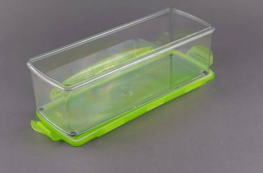 Gri arka planda yiyecek depolamak için kapağı olan dikdörtgen plastik bir kap. Yeşil kilit kapaklı şeffaf bir kutu. Yakın plan. Seçici odak.