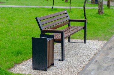 Yeşil bir çimenliğin arka planında ıslak boş bir park tezgahı. İlkbaharda dinlenme alanı. Yağmurdan sonra boş park.