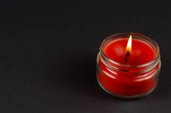 在黑色背景的玻璃瓶里点燃的红色蜡烛 在半明半暗的情况下 蜡蜡烛的火焰 侧视图 复制空间 — 图库照片