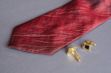 Kırmızı kravat ve gri arka planda sarı kol düğmeleri. Erkek aksesuarları.