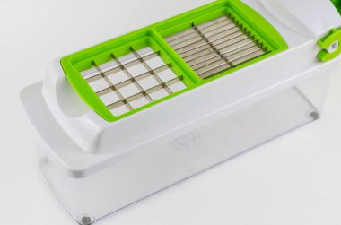 Beyaz arka planda manuel sebze kesicisi. Şeffaf bir konteynırda özel bıçak ve eklentiler. Mutfak aletleri.