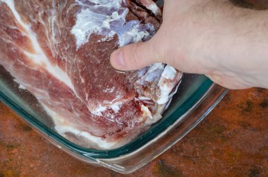 Ev yapımı Capicola (coppa). Kurutulmuş domuz filetosu adım adım tarifi. Sırılsıklam olmuş. El, tuzlanmış eti bir kap suya daldırır. Geleneksel İtalyan mutfağı.