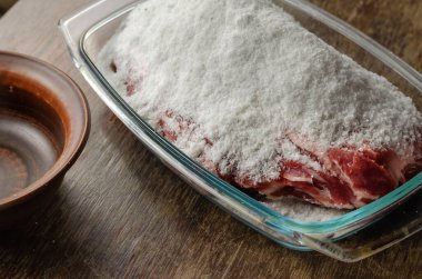 Ev yapımı Capicola (coppa). Kurutulmuş domuz filetosu adım adım tarifi. Adım tuzlama eti. Cam kasede tuzla kaplı çiğ domuz eti. Geleneksel İtalyan mutfağı.