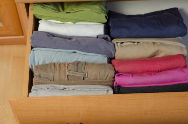 Dikey Japon giysi depolama sistemi kavramı. Konmari metodunu kullanarak şifoniyer rafına istiflenmiş çok renkli gömlekler..