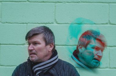 Çifte Kişilik Konsepti. Çoklu erkek portresi, çift taraflı arıza etkisi. Tuğla duvara karşı düşüncelere dalmış yetişkin bir adam. Çoklu pozlama, birleşik resim.