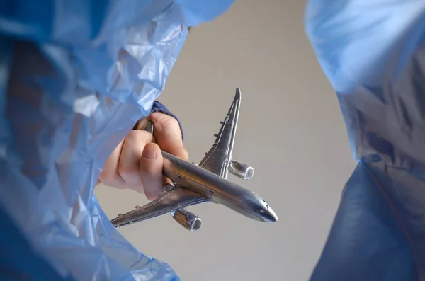 A man throws away a silver toy airplane. A hand holds a kid\'s model passenger airplane over a trash can. Bottom view.