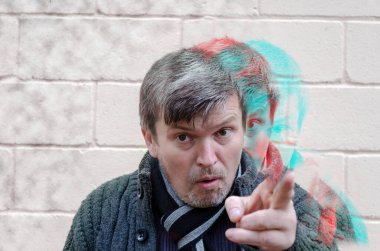 Psikolojik baskı, komuta, despotizm kavramı. Yetişkin, gergin bir adam işaret parmağıyla tuğla duvara doğru hareket ediyor. Hatalı duotone etkisi olan birden fazla erkek portresi.