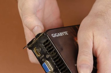 Graphics kart markası Gigabyte NVidia GeForce kahverengi arka planda. Adamın elinde Dusty bilgisayar parçaları var. Onarım, bilgisayar konsepti bakımı. Kiev, Ukrayna - 05 19 2021