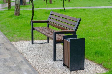 Yeşil bir çimenliğin arka planında ıslak boş bir park tezgahı. İlkbaharda dinlenme alanı. Yağmurdan sonra boş park.