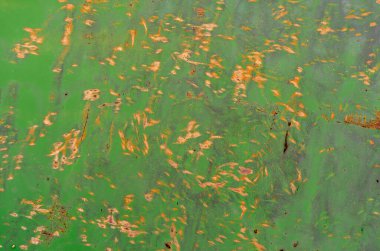 Kaotik sarı noktalar ve yeşil boyanmış metal duvardaki pas lekeleri. Paslı metal ve boya. Aşınmış metal arkaplan.