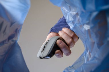 El, kablosuz bir bilgisayar faresini çöp kutusuna attı. Yetişkin bir erkek, çöp kutusunun üzerinde kontrol ve bilgi girişi için gri bir cihaz tutuyor. Alt görünüm.