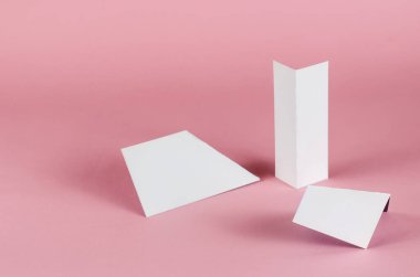 Pembe arka planda beyaz soyut geometrik şekiller. Renkli arka planda gölgeli üç rastgele geometrik şekil. Seçici odak.