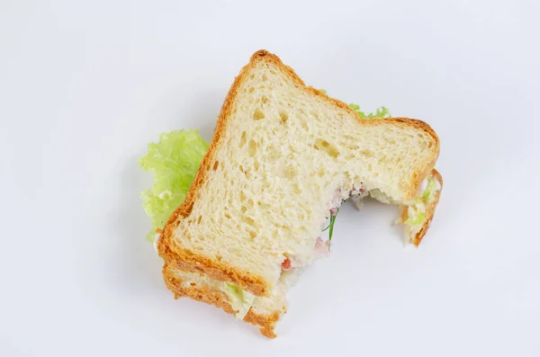 Beyaz arka planda yarısı yenmiş hindili sandviç. Hindi, kırmızı domates, yeşil marul, dereotu ve beyaz sos. Yemek artıkları. Üst görünüm