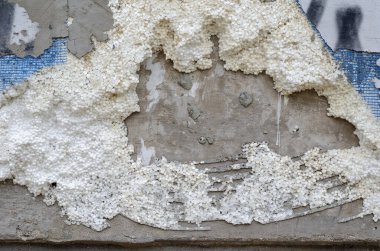 Binanın dış duvarının yalıtımı yok edildi. Dış cephenin çok katmanlı ses termal yalıtımı vandallara zarar vermiş. Beton duvar, köpük tahta, mavi ızgara, alçı. İnşaat, endüstri.