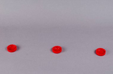 Kırmızı şişe önleyiciler arka planda. Üç plastik meşrubat durduruculu minimalist kompozisyon.