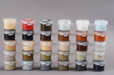 Gainsboro 'nun arka planında numaralandırılmış plastik boya kutuları var. Dikey olarak yerleştirilmiş pastel renklerde akrilik boya seti. Resim eğitimi, ev eğlencesi konsepti..