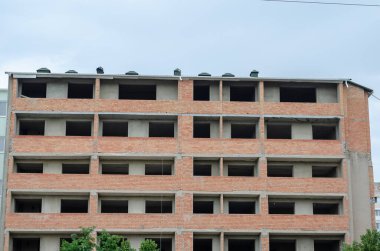 Bitmemiş bir binanın dokusu bulutlu bir gökyüzüne karşı. Penceresi ve kapısı olmayan kırmızı tuğlalı bir daire. Mimarlık, Sanayi, Gayrimenkul.