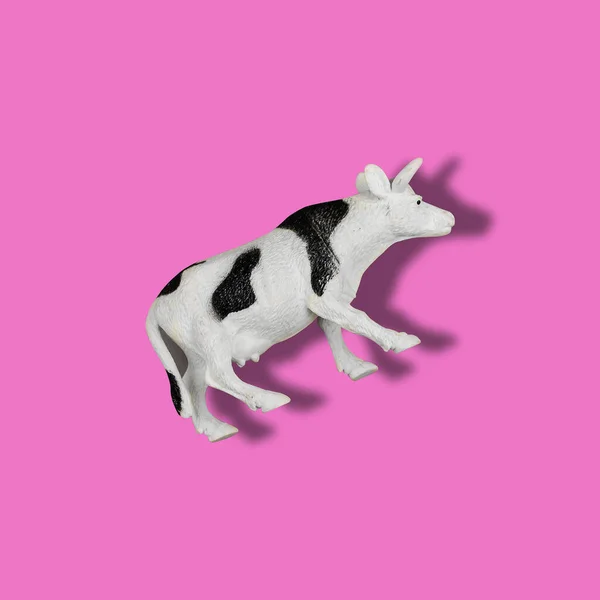 色付きの背景におもちゃの牛 ピンクの表面に隔離された黒と白の斑点のあるプラスチック動物のフィギュア 農場の動物 — ストック写真