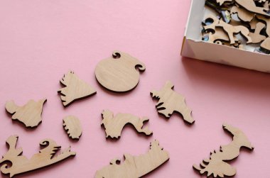 Pembe arka planda ahşap yapboz. Son derece doğru şekiller ve eklemlerden oluşan karmaşık bir bulmaca. Aktif boş zaman. Mantık oyunları.