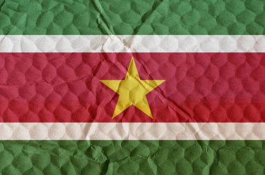 Flag of The Republic of Suriname on an uneven textured surface. The national flag of the country is on the northeast coast of South America. The concept of national pride, freedom, independence.
