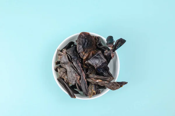 Training treats for pets on blue background. Natural Air Dried dog treats in a white ceramic bowl. Yummy Thin slices of dehydrated beef kidneys. Top view