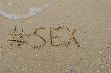 Etiket ve ıslak kuma yazılmış SEX kelimesi. Sahilde el yazısıyla yazılmış bir kelime. Yukarıdan bir açıyla görüntüle.