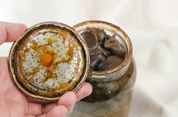 Botulizm, konserve gıda konservesinden zehirlenme. Paslı teneke kapaklı, siyah lekeli tutamaklar. Ev yapımı Suillus turşulu cam kavanoz. Bozulmuş orman mantarları.