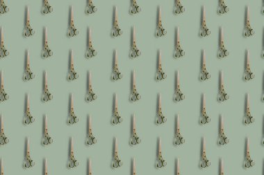 Repeated Old tailor scissors vertically on colored background. Vintage metal hand tools. Craft, background.