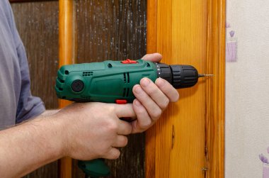 Bir adam vidayı kapı çerçevesinden söker. Tahta kapı süslemesini söküyorum. Tornavida kullanıyor. Tesis onarım servisi. Seçici odak.