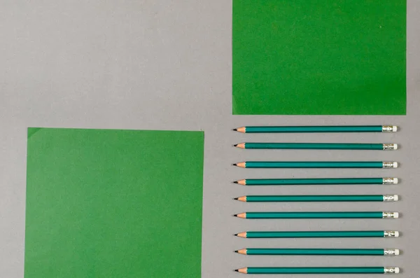 一套木制铅笔和绿色的纸 背景是灰色的 铅笔和二次纸 顶部视图 — 图库照片