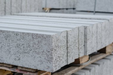 Paletlerin üzerine yığılmış gri kaldırımlar. Yeni beton kaldırımlar birbirine bantlanmış. Tamir ve inşaat işleri. Dışarı çıkın. Seçici odaklanma. Kimse yok..