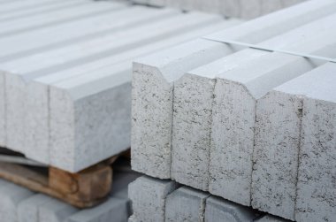 Paletlerin üzerine yığılmış gri kaldırımlar. Yeni beton kaldırımlar birbirine bantlanmış. Tamir ve inşaat işleri. Dışarı çıkın. Seçici odaklanma. Kimse yok..