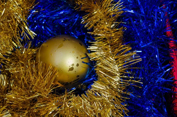 Uma bola de Natal dourada está em uma caixa em cima de azul e amarelo — Fotografia de Stock