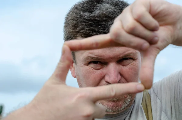 Retrato de um homem adulto a fazer uma moldura dos dedos. A gra — Fotografia de Stock