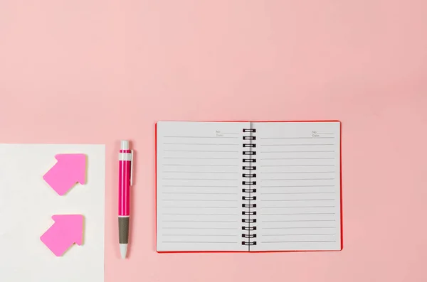 Feuilles de papier, carnet ouvert, signets fléchés, stylo sur bac rose — Photo