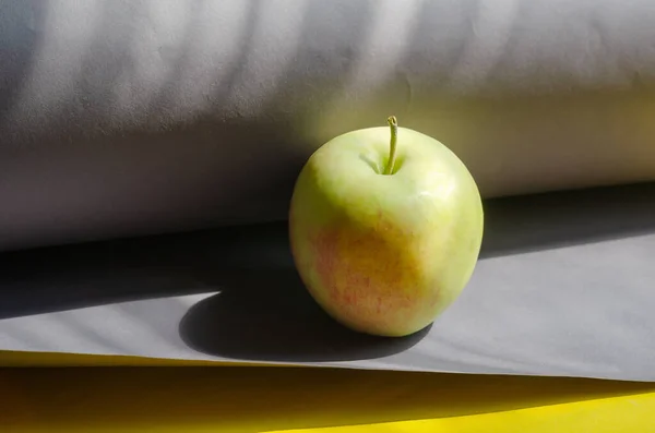 Спелое яблоко на серо-желтом фоне. Готовые к употреблению фрукты — стоковое фото