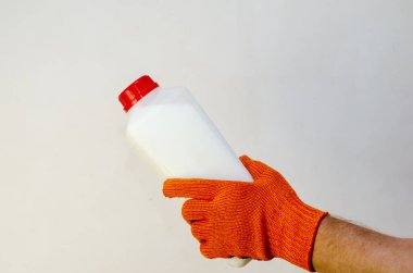 Kırmızı koruyucu eldivendeki bir el yine plastik bir kap tutuyor.