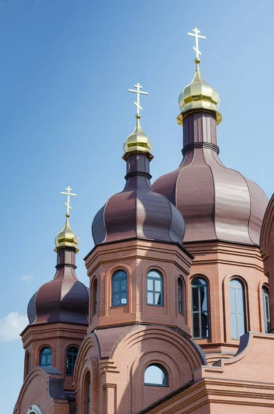 Uma igreja ortodoxa cristã em frente a um céu azul claro. Um bri vermelho — Fotografia de Stock