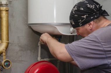 Su ısıtıcısı uzmanı kazan dairesinde çalışıyor. Yetişkin bir mal