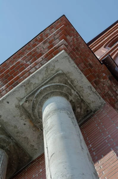 A gray cement column. Concrete column of a red brick building. C