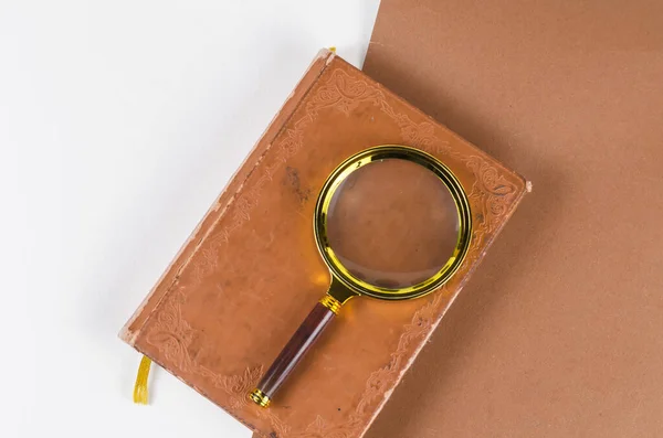 Förstoringsglas och en gammal anteckningsbok på en tvåfärgad bakgrund. — Stockfoto