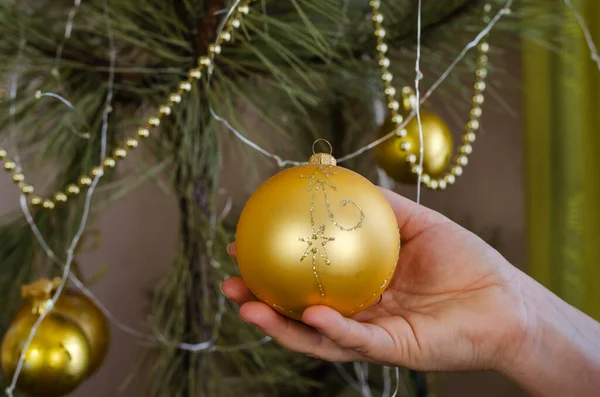 Een vrouw die een kerstboom versiert. Volwassen vrouw hangt feestelijke bal — Stockfoto