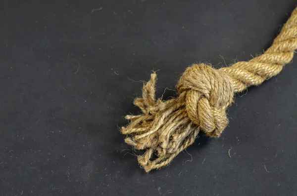 Cuerda de yute con un nudo sobre un fondo negro. La cuerda retorcida está loca. —  Fotos de Stock