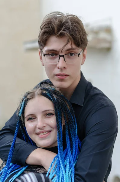 Man with glasses hugs woman with blue pigtails from behind. Hete — Stock Photo, Image