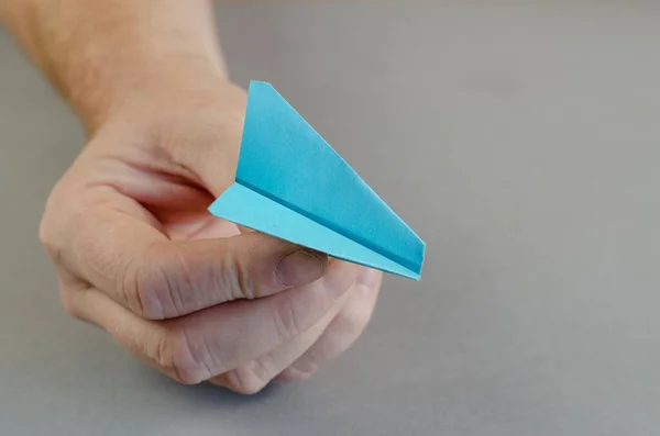 Uma mão de homem segura um avião de papel azul. Pessoa detentora de um ou — Fotografia de Stock