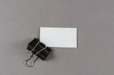 Boş beyaz kartvizit ve siyah ataç, gri bir bala karşı.