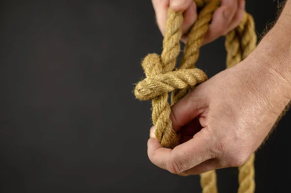 Een volwassen mannetje spookt touw tegen een zwarte achtergrond. Handen omhoog. — Stockfoto