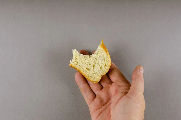 Una mano sostiene una mitad mordida de una rebanada de pan de trigo. Una madre adulta —  Fotos de Stock