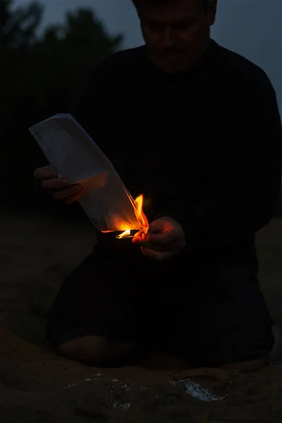 Um homem adulto agarra-se aos documentos em chamas. Folhas arrancadas — Fotografia de Stock