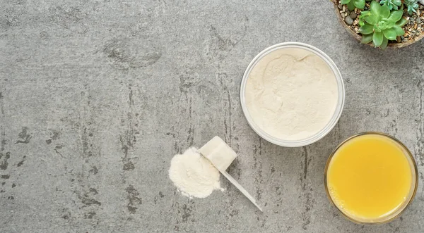 Collagen protein powder in a plastic measuring spoon and jar on a gray stone background, flat lay. Supplemental protein supplementation for body and joint health. On a natural basis. Space for text